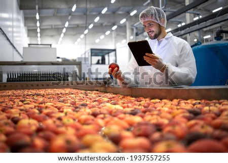 Technologist doing quality control of apple fruit production in food processing plant. Royalty-Free Stock Photo #1937557255