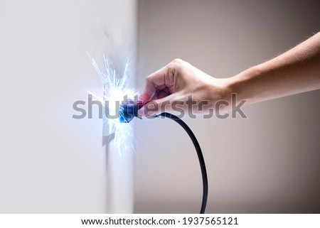 Hand connecting electrical plug cause electric shock, Idea for causes of home fire, Electric short circuit, Electrical hazard can ignite household items, Residential building electrical fires. Royalty-Free Stock Photo #1937565121