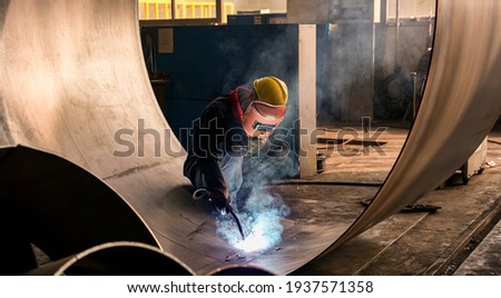 Asian workers are hard welding iron plates in the factory