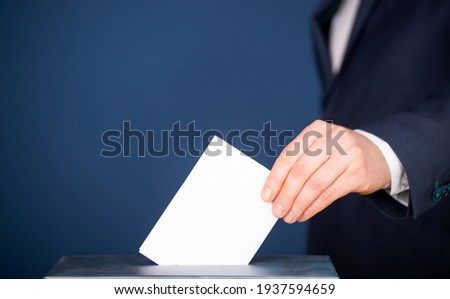 Hand of a voter putting vote in the ballot box. Election concept. Royalty-Free Stock Photo #1937594659