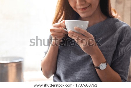 Closeup image of a beautiful young asian woman smelling and drinking hot coffee