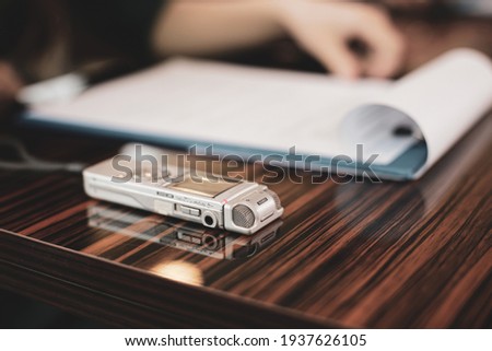 Shallow depth of field (selective focus) image with an audio recorder of a woman journalist during an interview. Royalty-Free Stock Photo #1937626105