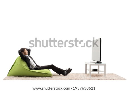 Professional man in a suit sitting on a green bean bag chair and watching tv isolated on white background