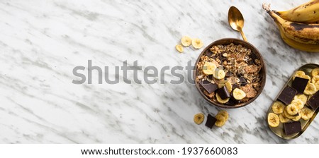 Muesli made from mix of unprocessed whole grains, chia, quinoa, nuts, seeds, with banana and chocolate in coconut vowl on the large background for banner.