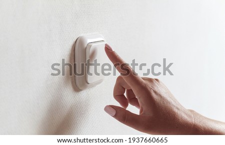 Female hand turns off the light indoors. Energy saving concept.
