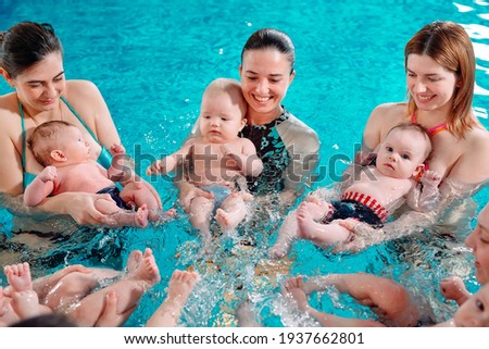 A group of mothers with their young children in a children's swimming class with a coach Royalty-Free Stock Photo #1937662801