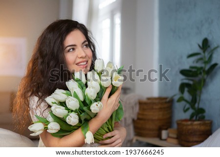 Portrait of a beautiful young woman with bunch of white tulips.
