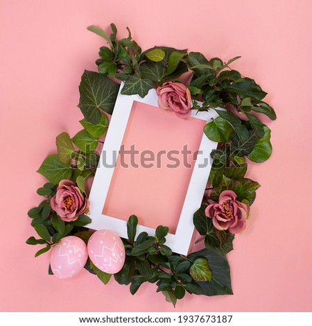 Easter composition. Easter eggs, photo frame, white flowers on pastel pink background. Flat lay, top view, copy space stock