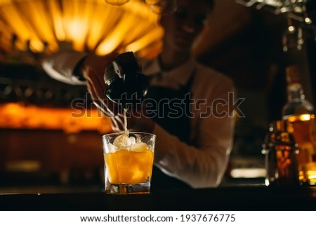 The bartender squeezes citrus juice into a cocktail Royalty-Free Stock Photo #1937676775