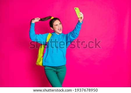 Photo of cute excited young lady wear blue sweater rucksack making selfie modern device holding tail isolated pink color background