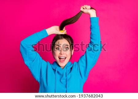 Photo of impressed cheerful lady open mouth arms hold play with hair tail isolated on pink color background
