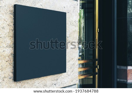 Black square sign with blank space for your logo on the marble wall of a modern business center, mockup