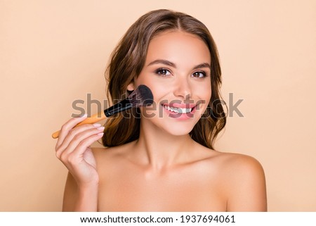 Photo of young happy smiling beautiful woman doing contouring apply blush on cheeks isolated on beige color background Royalty-Free Stock Photo #1937694061