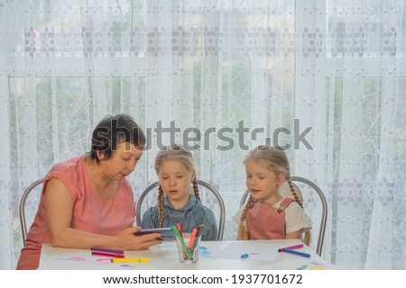 grandmother shows two granddaughters a drawing lesson on the phone home
