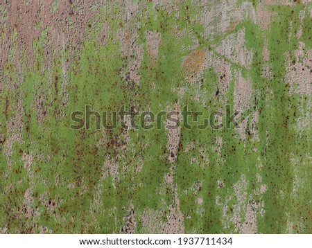 A fragment of a metal surface covered with cracked light green paint and rust