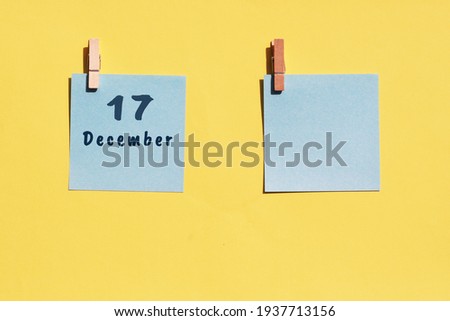 17 December. 17th day of the month, calendar date. Two blue sheets for writing on a yellow background. Top view, copy space. Winter month, day of the year concept.