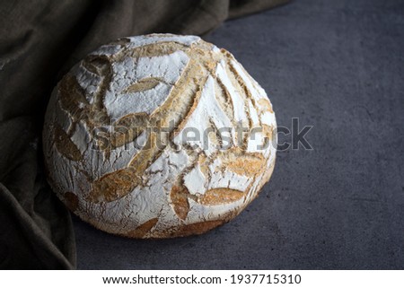 Round sourdough bread on a table. Crusty loaf texture close up. Top view photo of freshly baked artisan bread. Gray textured background. Healthy eating concept. 