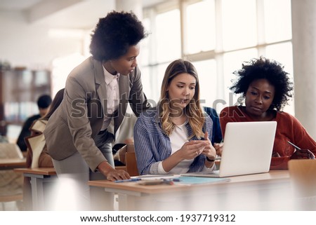 Female students communicating with their teacher while using computer during lecture in the classroom.  Royalty-Free Stock Photo #1937719312