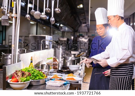 The male executive chef discussing the menu with his colleague in the kitchen.Food and restaurant concept. Royalty-Free Stock Photo #1937721766