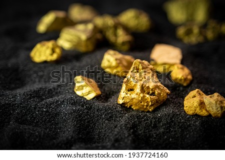 Pure gold from the mine that was unearthed was placed on the black sand. Royalty-Free Stock Photo #1937724160