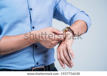 Setting clock going. Man wind wrist watch grey background. Portable timepiece. Time management. Deadline. Clock is ticking Royalty-Free Stock Photo #1937756638