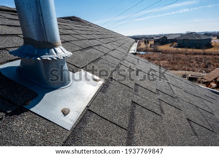 Vent on a shingle roof with silicon caulking and flashing for a water tight seal Royalty-Free Stock Photo #1937769847