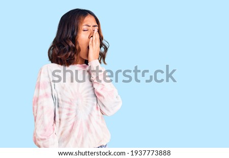 Young beautiful mixed race woman wearing casual tie dye sweatshirt bored yawning tired covering mouth with hand. restless and sleepiness. 