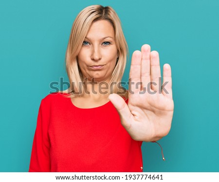 Middle age caucasian woman wearing casual clothes doing stop sing with palm of the hand. warning expression with negative and serious gesture on the face. 