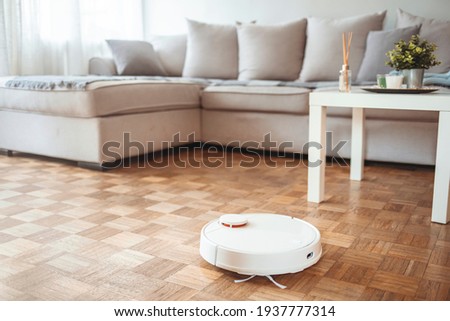 Blurred background of interior apartment with a robot vacuum cleaner that moves independently on a house with wooden parquet. Background neutral for modern apartment