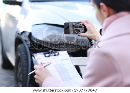 Insurance agent taking pictures of wrecked car closeup