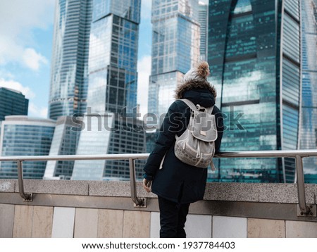 Young beautiful woman and Moscow City international business center in the background. Cold Winter day. Travel to Russia