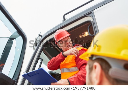 Truck drivers from the haulage company and construction workers on the road construction site Royalty-Free Stock Photo #1937791480