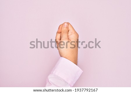 Hand of caucasian young man showing fingers over isolated pink background holding blank space with thumb finger, business and advertising