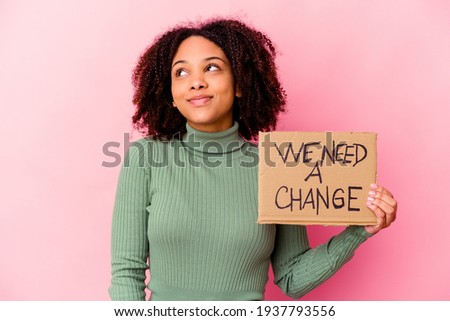 Young african american mixed race woman holding an inspiring message cardboard dreaming of achieving goals and purposes