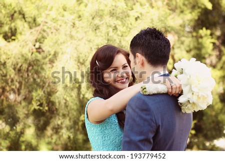 Happy couple on their ceremony day, bride holding peonies bouquet