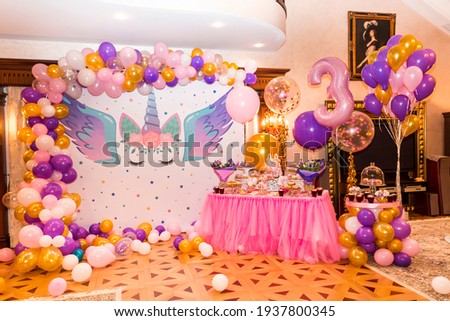 Little girl birthday party table with unicorn cake, cupcakes, and sugaer cookies Royalty-Free Stock Photo #1937800345