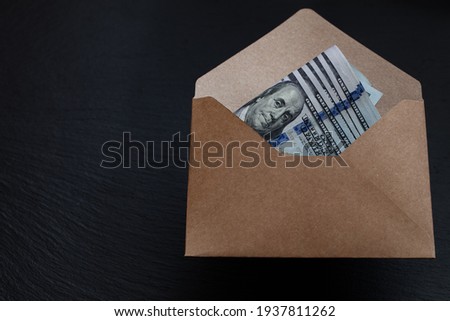 US 100 dollar banknote in handmade envelope on black background 