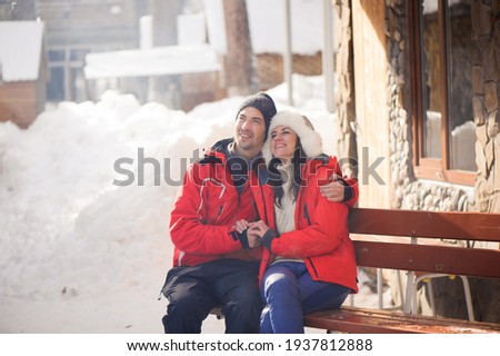 Picture of family couple in a winter clothes sitting on a wooden bench.