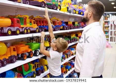 Dad with a small child at the rows of toys in a children's store. Royalty-Free Stock Photo #1937819941