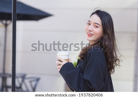 Asian beautiful woman in a dark blue suit is stand smile happy. In front of the coffee shop in the sunny morning