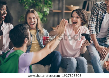 Photo of happy excited young people high five teamwork play game at party good mood indoors inside house