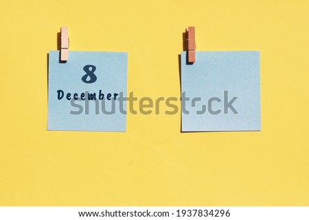 8 December. 8th day of the month, calendar date. Two blue sheets for writing on a yellow background. Top view, copy space. Winter month, day of the year concept.