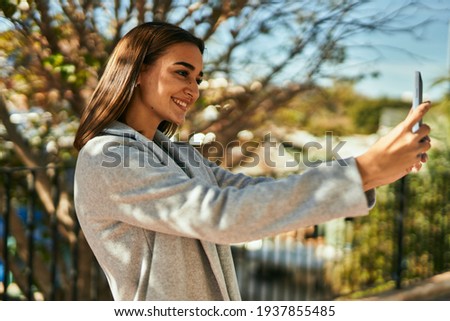 Young hispanic girl smiling happy making selfie by the smartphone at the city.