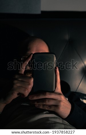 Young bearded male on a smartphone in bed. Nightlife. Relaxing. Social media.