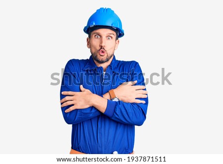 Young handsome man wearing worker uniform and hardhat pointing up looking sad and upset, indicating direction with fingers, unhappy and depressed. 