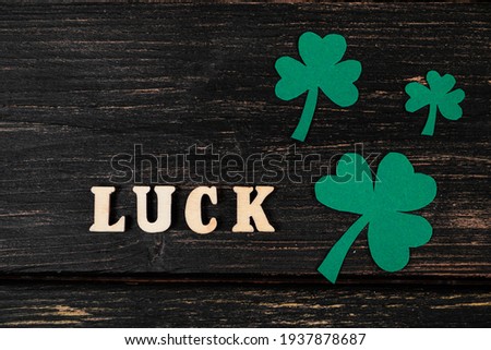 Flatlay for St. Patrick's Day. Shamrock clover leaves on dark wooden background. Happy Irish holiday, symbols of good luck.