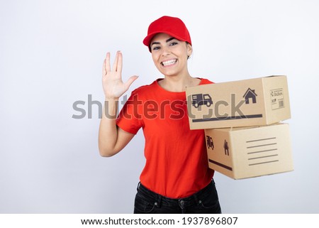 Young beautiful woman wearing courier uniform holding delivery packages doing hand symbol