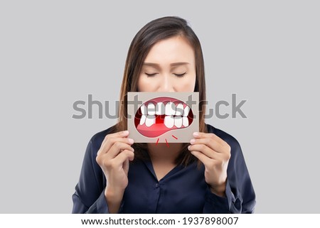 Asian woman in the dark blue shirt holding a brown paper with the broken tooth cartoon picture of his mouth against the gray background, Decayed tooth, The concept with healthcare gums and teeth