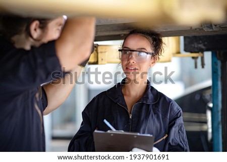 Hispanic Female trainee Mechanics Working Underneath Car Together Car maintenance and auto service garage. Car maintenance and auto service garage concept.  Royalty-Free Stock Photo #1937901691