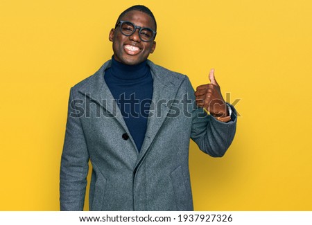 Young african american man wearing business clothes and glasses doing happy thumbs up gesture with hand. approving expression looking at the camera showing success. 